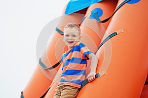 Little boy playing on an inflatable playground on the beach