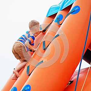 Little boy playing on an inflatable playground on the beach