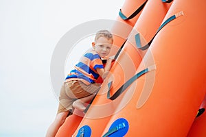 Little boy playing on an inflatable playground on the beach