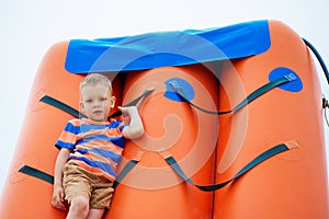 Little boy playing on an inflatable playground on the beach