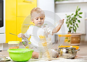 Little boy playing with kitchenware and foodstuffs