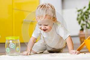 Little boy playing with kitchenware and foodstuffs in kitchen