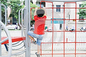 Little boy playing on monkey bars at playground