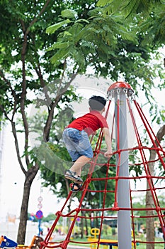 Little boy playing on monkey bars at playground