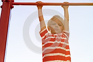 Little boy playing on monkey bars in playground