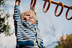 Little boy playing on monkey bars at playground