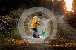 Little boy playing in a muddy puddle