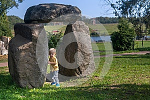 Little boy playing near big stones in the park on a sunny day