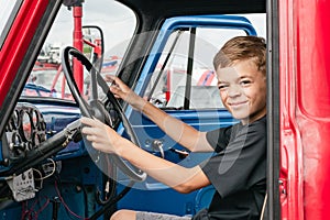 A little boy is playing near a car