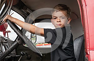 A little boy is playing near a car