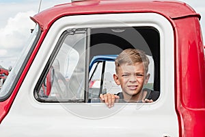 A little boy is playing near a car