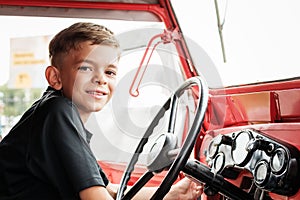 A little boy is playing near a car