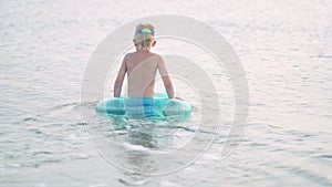 Little boy playing in ocean sea water, child having fun, swimming on blue swimming ring. Summer vacation, holiday