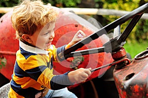 Little boy playing on old tractor