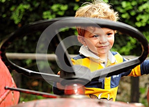 Little boy playing on old tractor