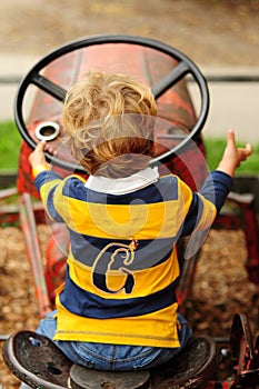 Little boy playing on old tractor