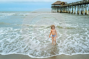 Little boy playing in outdoor jumping into water on summer vacation on tropical beach island. Happy child playing in the