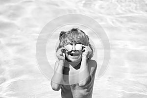 Little boy playing in outdoor swimming pool in blue water on summer vacation on tropical beach. Child learning to swim