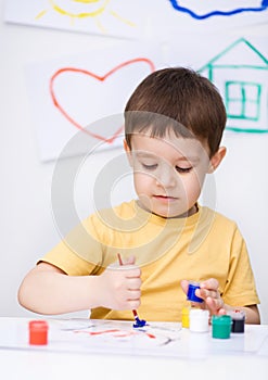 Little boy is playing with paints