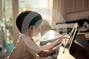 Little Boy playing with piano and Music Tablet at home