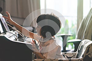 Little Boy playing with piano and Music Tablet at home