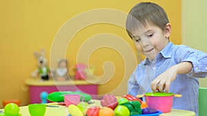 Little boy playing with plastic tableware in children`s room