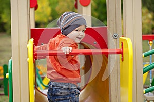 Little boy playing on the playground in the autumn park