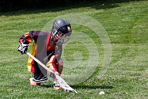 Little boy playing in protective gear lacrosse in the park