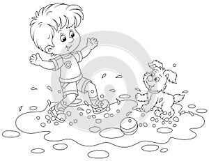 Little boy playing with a puppy in a puddle