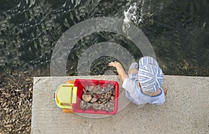 Little boy playing at riverside with dump truck full of stones