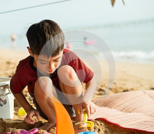 Little boy playing sand on the beach summer time