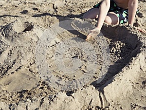 Little boy playing with sand on sunny day, closeup