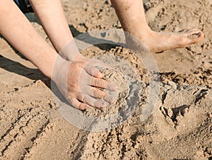 Little boy playing with sand on sunny day, closeup