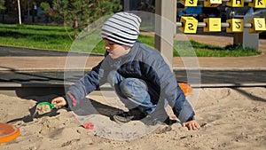 Little boy playing in sandpit on palyground and building sand castle. Concept of child development, sports and education