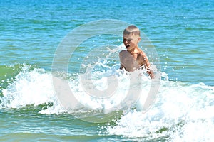 A little boy playing in the sea water. A child jumps from the sea. A tropical vacation with children.