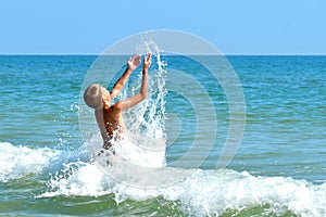 A little boy playing in the sea water. A child jumps from the sea. A tropical vacation with children.