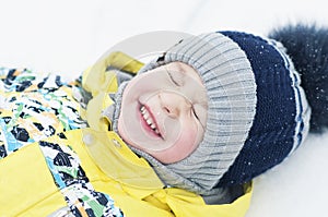 Little boy playing in the snow, portrait, lying on his back, laughing