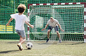 Little boy playing soccer, kicking ball to goal