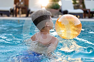 Little boy playing in swimming pool with beach ball