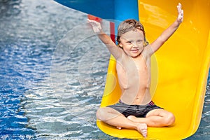 Little boy playing in the swimming pool on slide