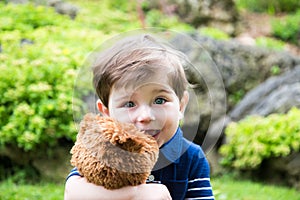 little boy playing with a teddy bear in the garden