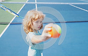 Little boy playing tennis. Sport kids. Child with tennis racket on tennis court. Training for young kid, healthy