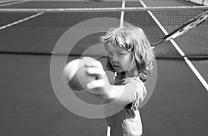 Little boy playing tennis. Sport kids. Child with tennis racket on tennis court. Training for young kid, healthy