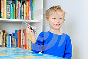 Little boy playing with toy airplane flying over