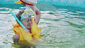 A little boy playing with a toy boat in the inflatable swimming pool