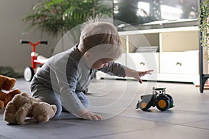 little boy playing with toy car in living room, blurred background