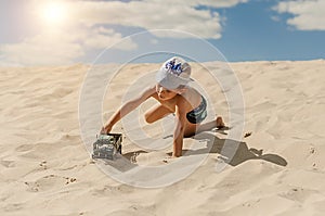 Little boy playing with a toy car on the sand
