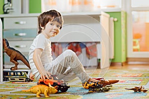 Little boy playing toy cars on play mat. Young kid with colorful educational vehicle and transport toys on carpet. City street map