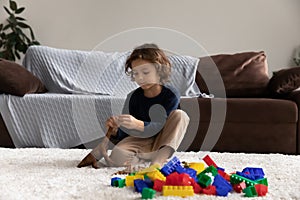 Little boy playing with toy dinosaur, sitting on warm floor