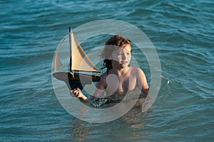 Little boy playing with toy sailing boat, toy ship. Travel and adventure concept. Child feeling adventurous while